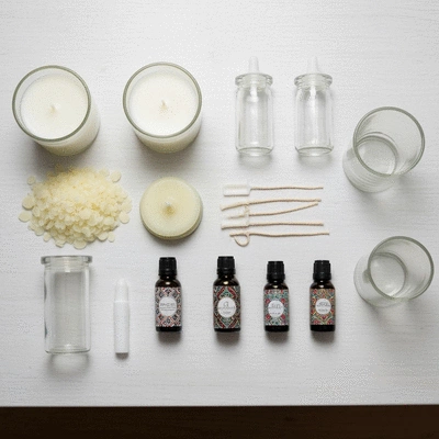 Assortment of candle making supplies including soy wax flakes, wicks, fragrance oils, and glass jars